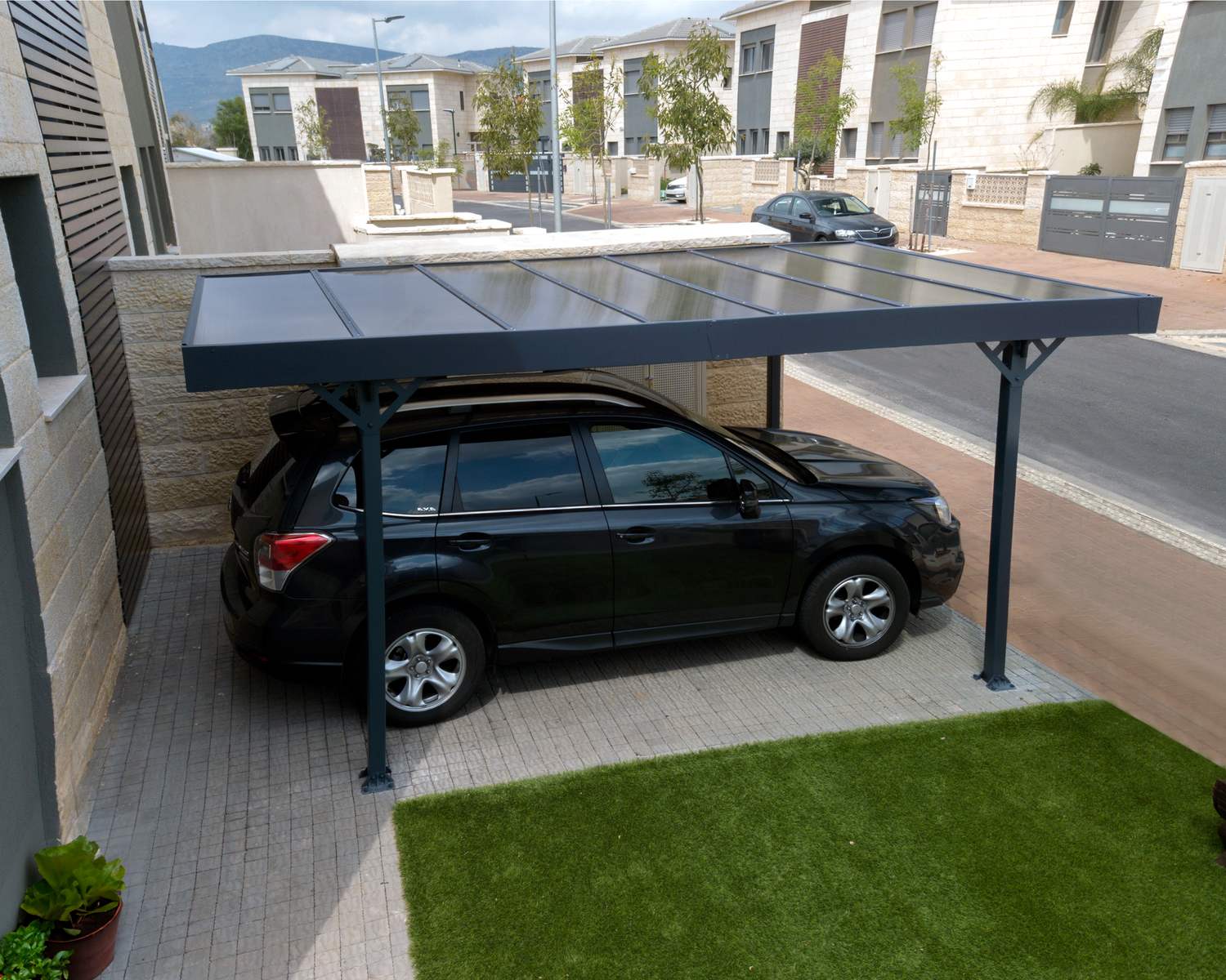 Grey 10ft x 16ft Palma aluminum carport with a flat roof, located in a lush garden next to a modern home