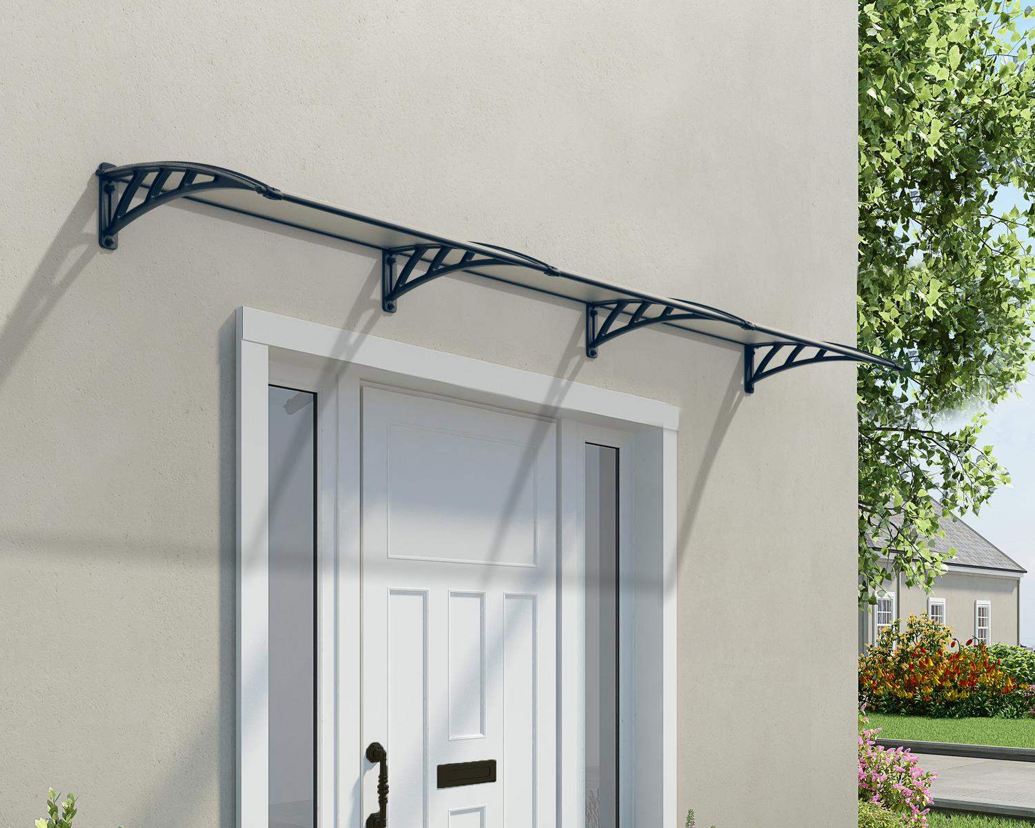 Grey twinwall Neo 2.5ft x 12ft door awning with a curved design, mounted above a window on a beige wall, featuring a vintage lantern