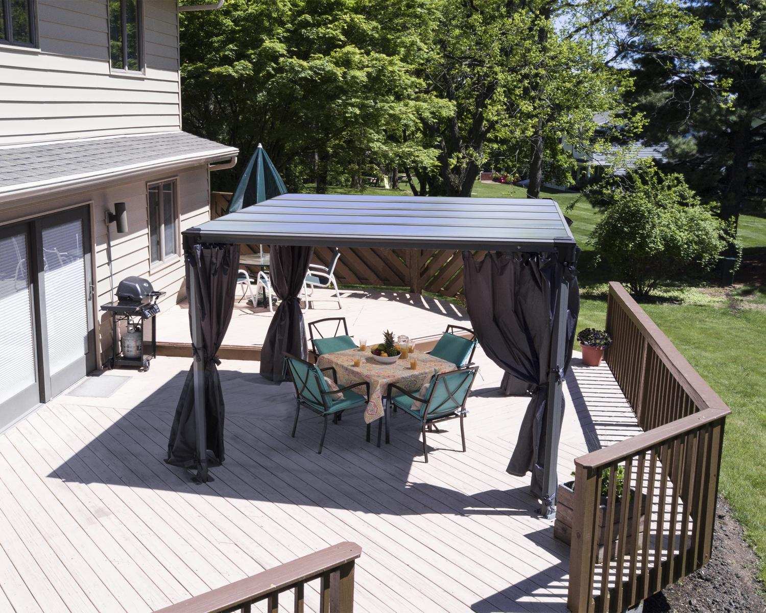 Milano 10ft x 10ft grey aluminum gazebo with a modern design, featuring a wicker sofa set surrounded by greenery