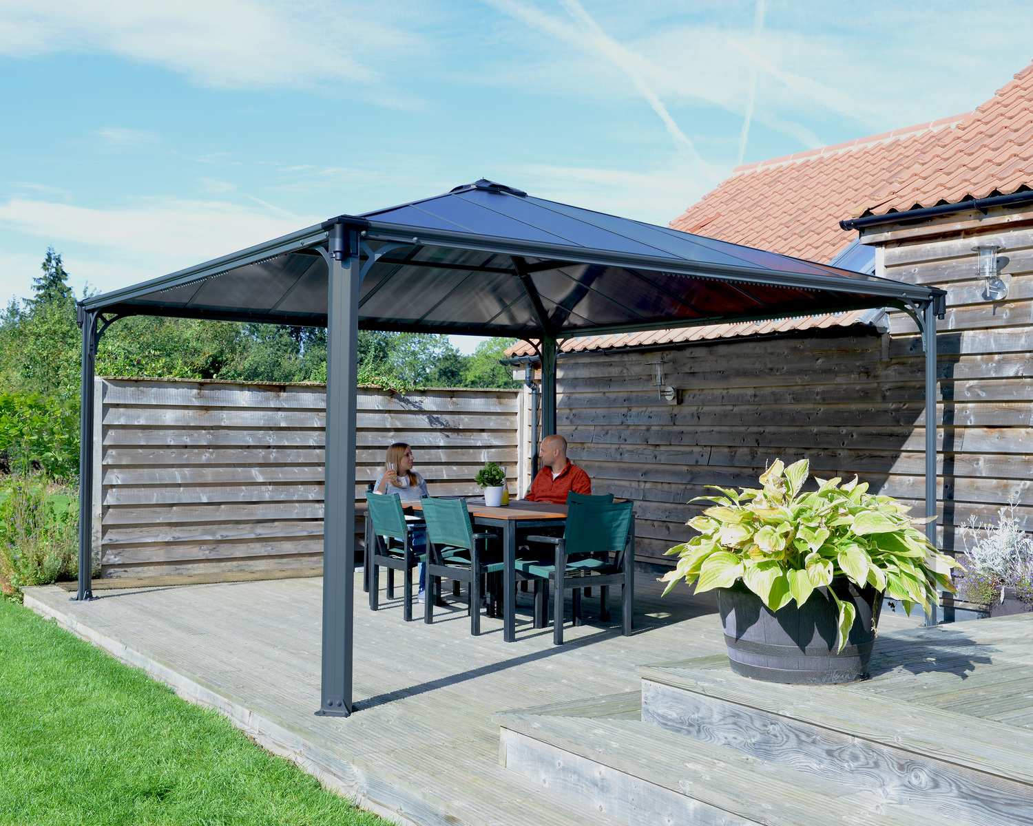 Palermo 14ft x 14ft grey aluminum gazebo with a modern design, sturdy frame, and spacious open structure, set on a deck with a green landscape