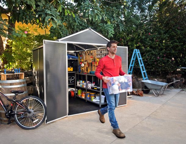 Rubicon 6' x 8' Plastic Garden Shed with Dark Gery Polycarbonate MultiWalls & Aluminium Frame. A person emerged from a shed with items.