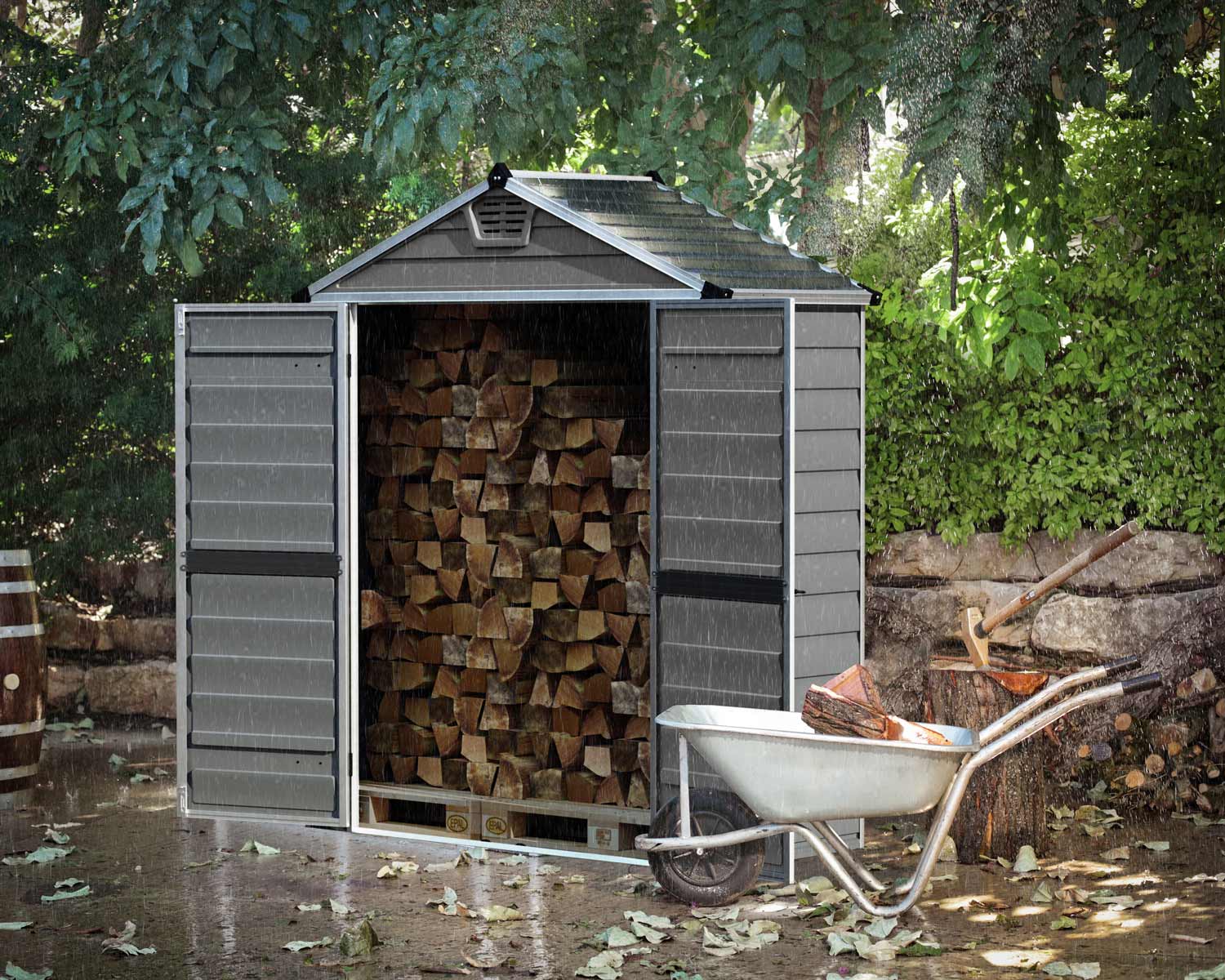 Grey Skylight plastic storage shed, 6 ft x 3 ft, filled with firewood, next to a wheelbarrow and axe, in the rain