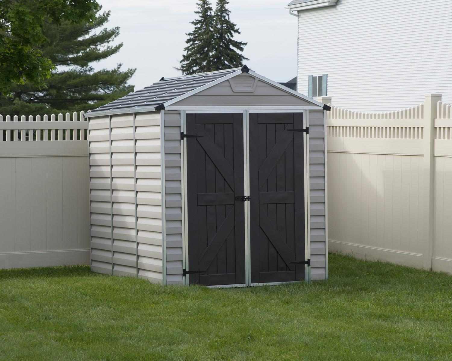Tan skylight plastic storage shed with double doors, 6 ft x 8 ft, in a grassy backyard surrounded by plants