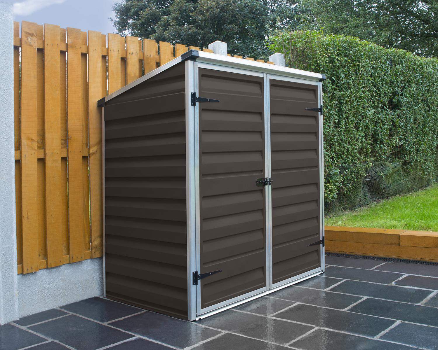 Voyager Plastic Storage Shed 2ft x 4ft in Brown, with a spacious interior, set on a paved surface beside a wooden fence