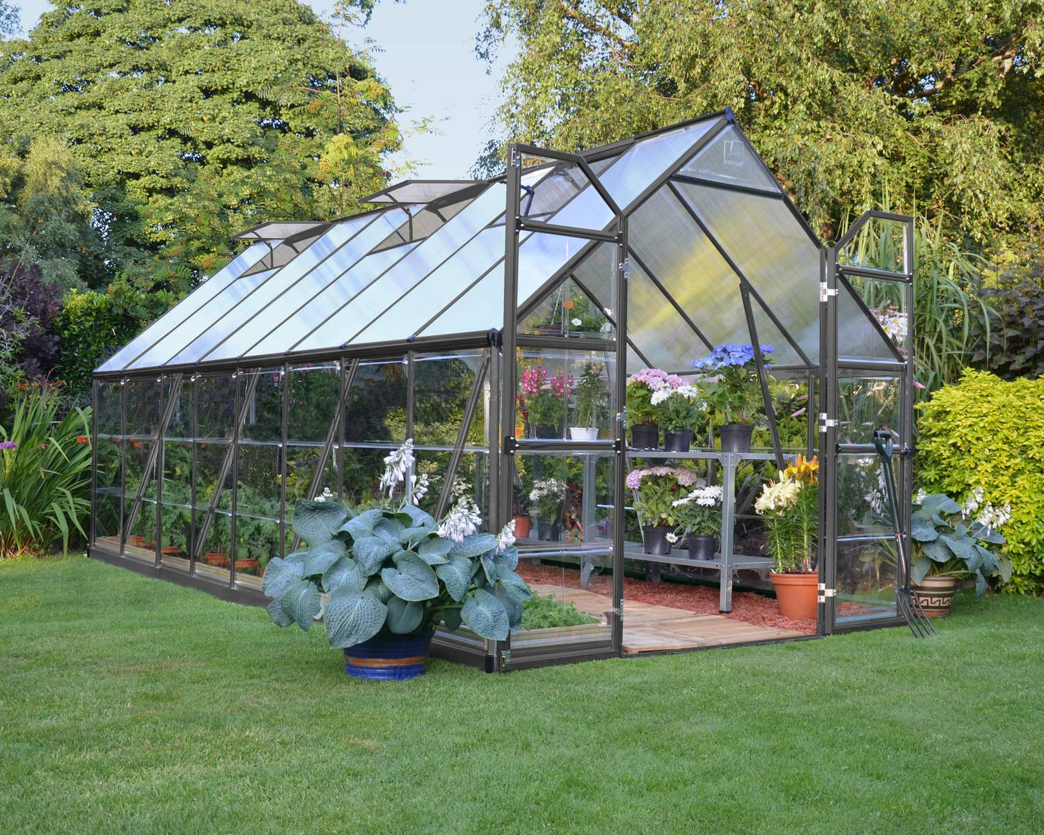 8ft x 16ft grey Balance greenhouse with polycarbonate panels and aluminium frame, surrounded by a lush garden