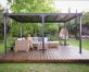Outdoor gazebo with a flat polycarbonate roof panels on a patio deck with garden furniture