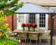 Garden gazebo grey aluminum with polycarbonate roof panels on a deck patio with dining furniture