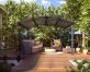 Arched aluminium pergola 11' x 14' on a patio deck with garden furniture