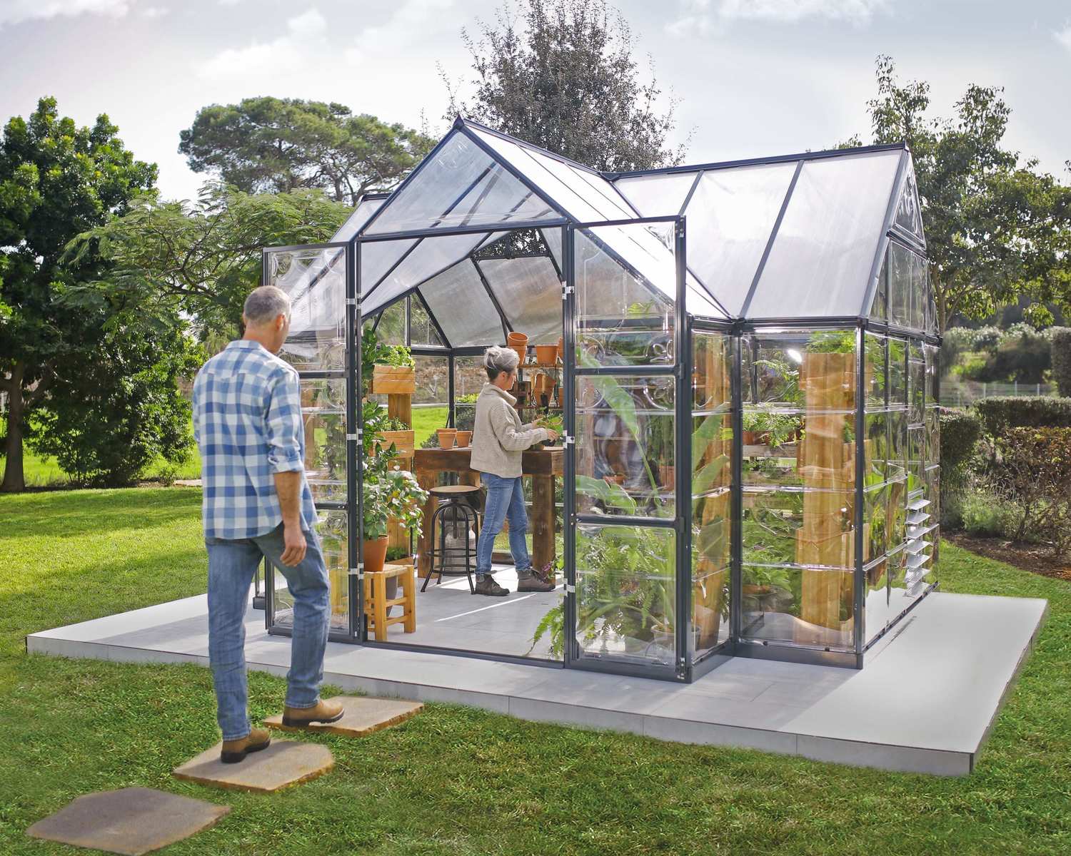 A person walks in a Victory Orangery 10' x 12' Garden Chalet on a lawn