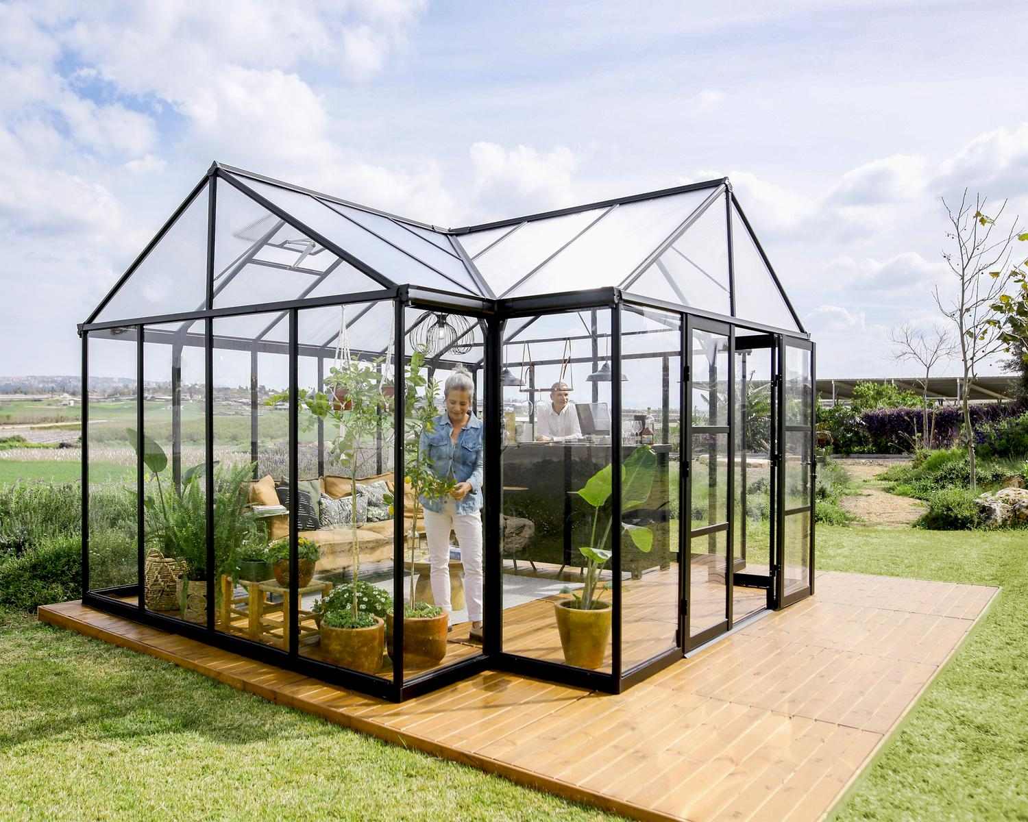 Triomphe 13ft x 15ft black greenhouse with clear polycarbonate panels, modern design, and durable frame, set amidst greenery