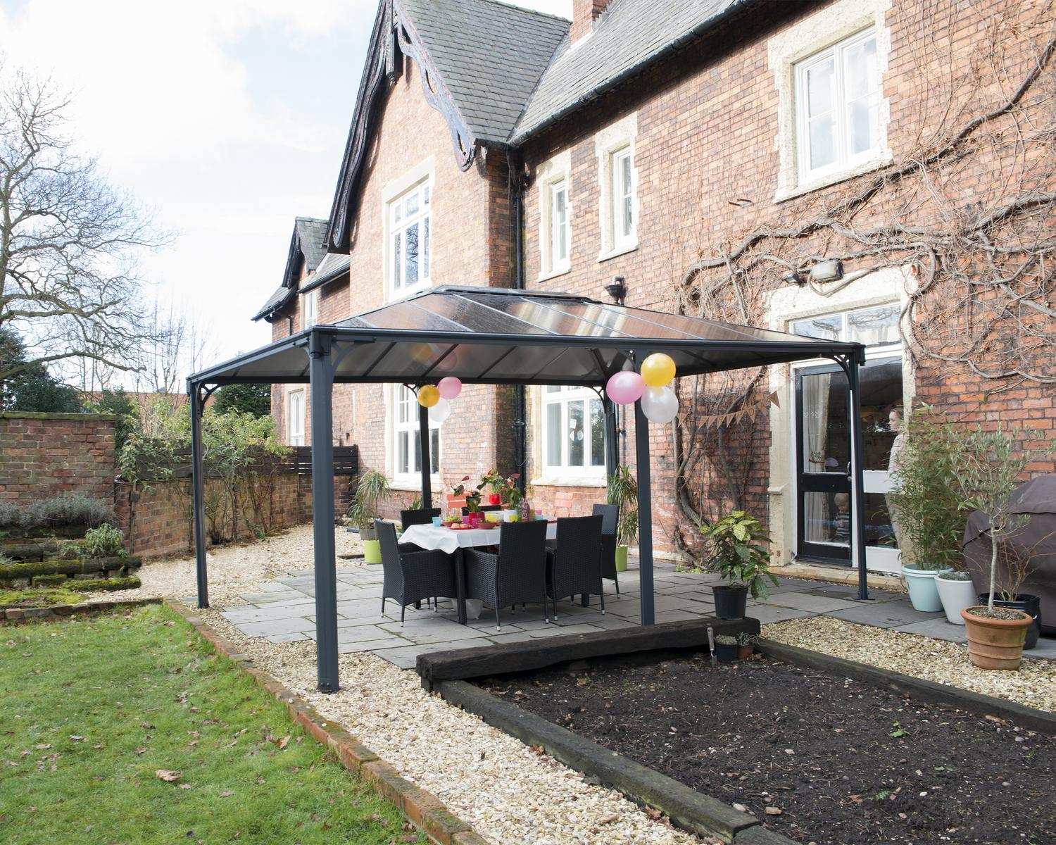 Martinique 12ft x 16ft grey aluminum gazebo with a sleek design, set in front of a brick house for a stylish outdoor retreat.