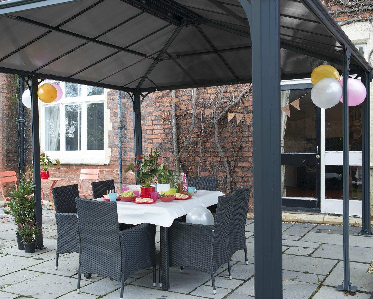 Martinique 12ft x 16ft grey aluminum gazebo with a sleek design, set in front of a brick house for a stylish outdoor retreat.