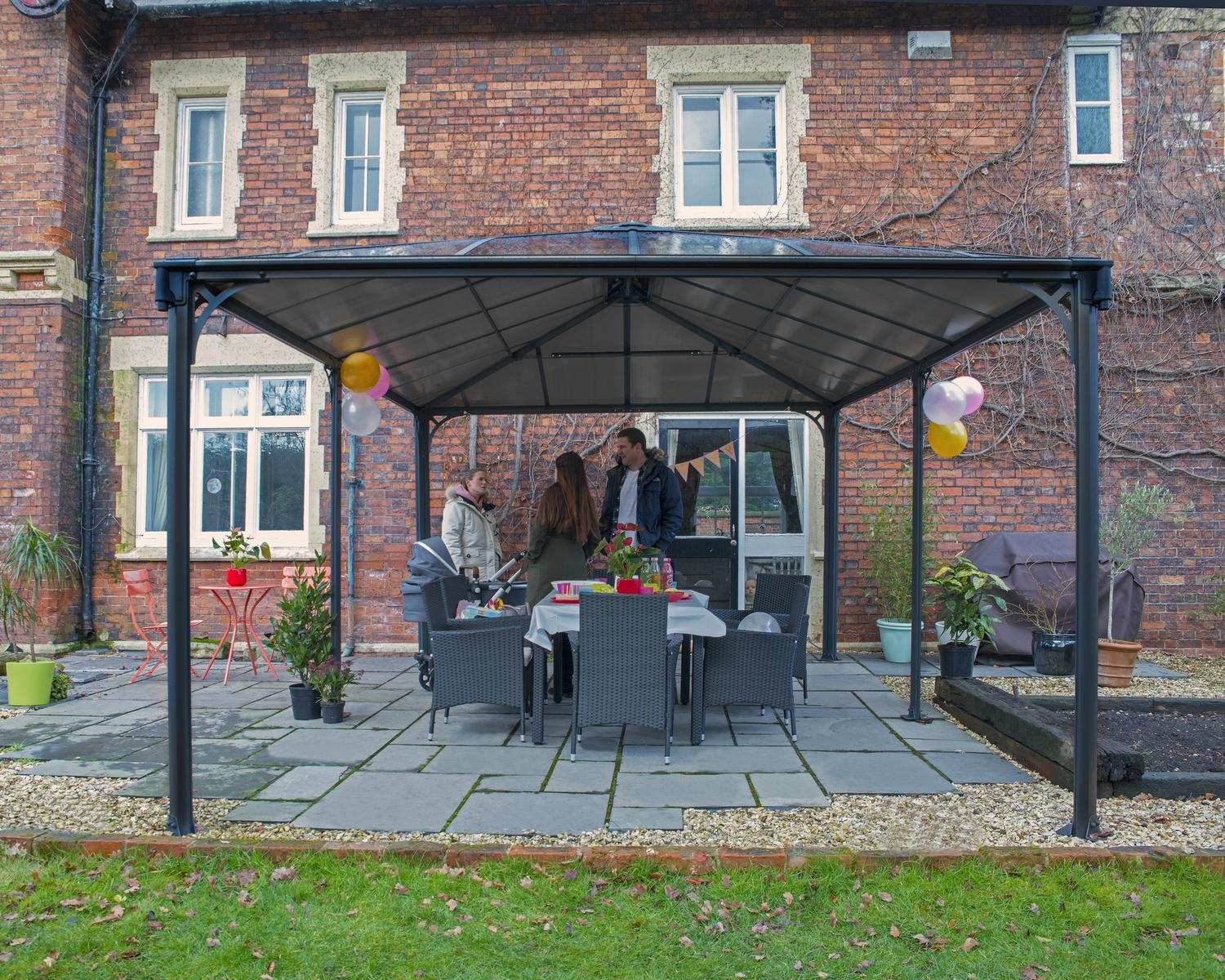 Martinique 12ft x 16ft grey aluminum gazebo with a sleek design, set in front of a brick house for a stylish outdoor retreat.
