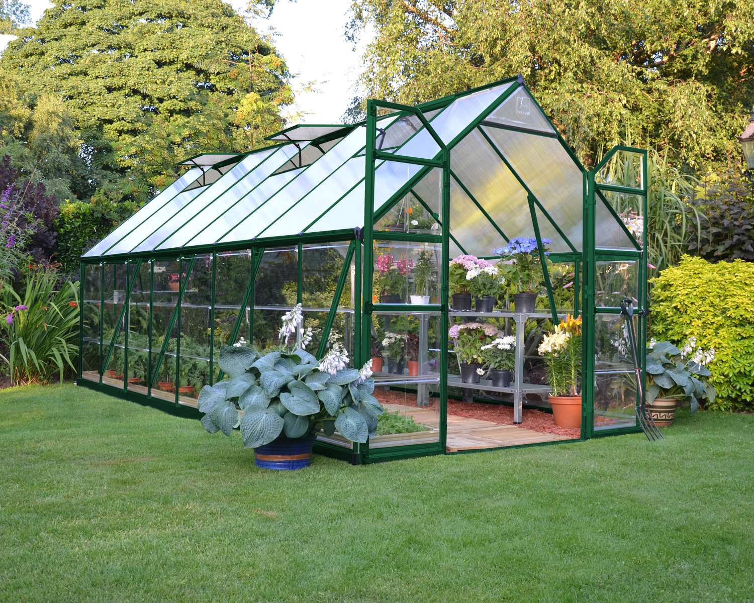 8ft x 16ft green Balance greenhouse with polycarbonate panels and aluminium frame, filled with plants in a lush garden