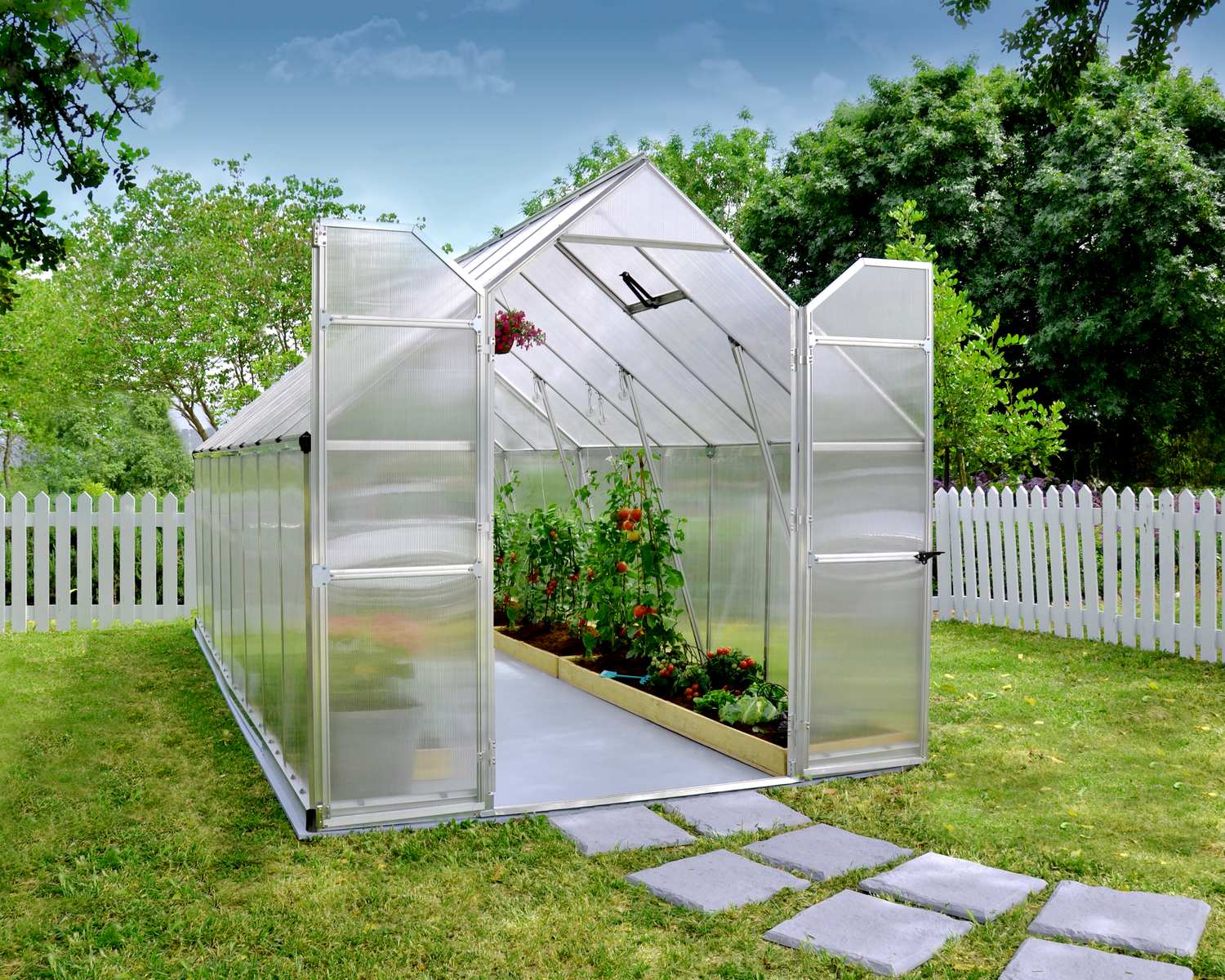 Essence 8x16 Silver greenhouse with polycarbonate panels, double doors, and a sloped roof, set amidst autumn trees