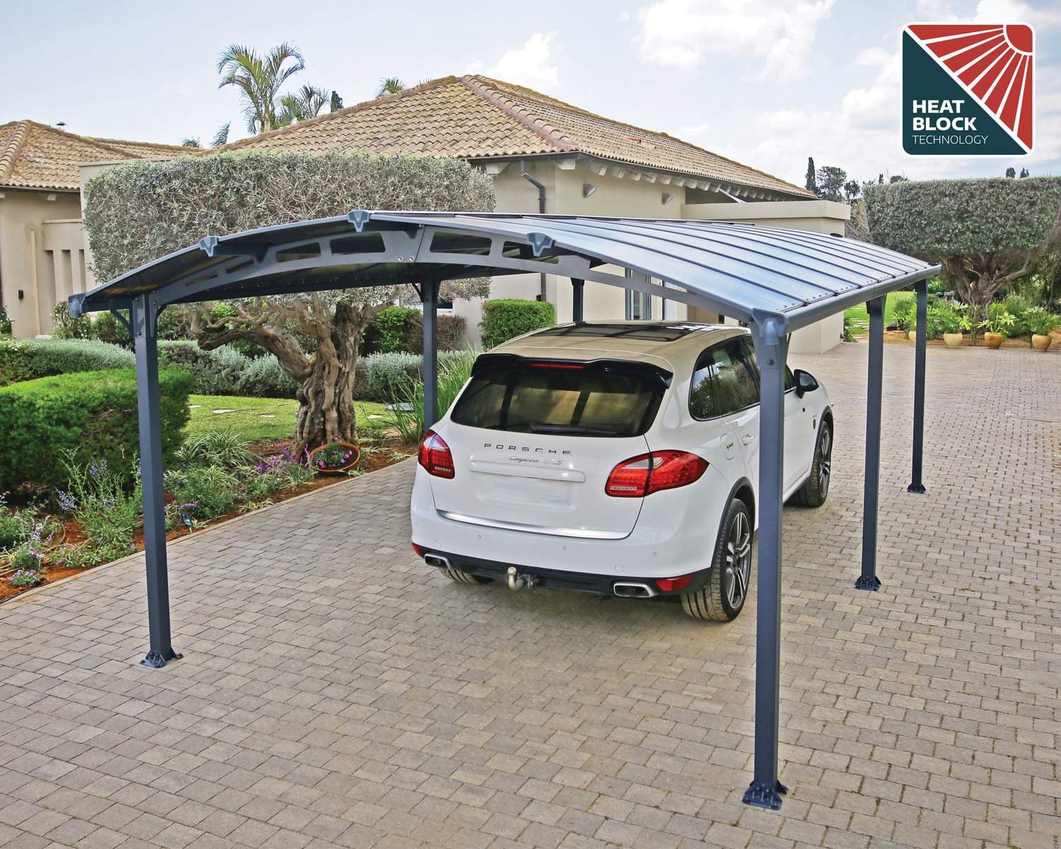 12ft x 21ft Arcadia carport with a grey aluminum frame and polycarbonate roof, sheltering a white pickup truck next to a brick house