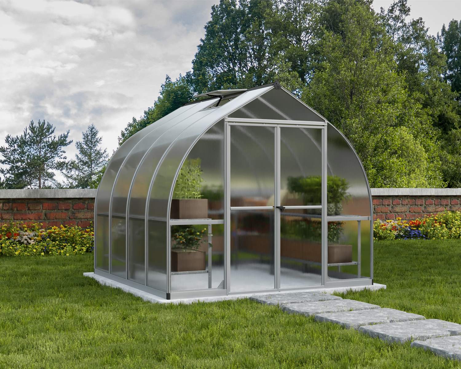 8ft x 8ft silver Bella greenhouse with an aluminum frame and clear polycarbonate panels, set in a garden with plants around
