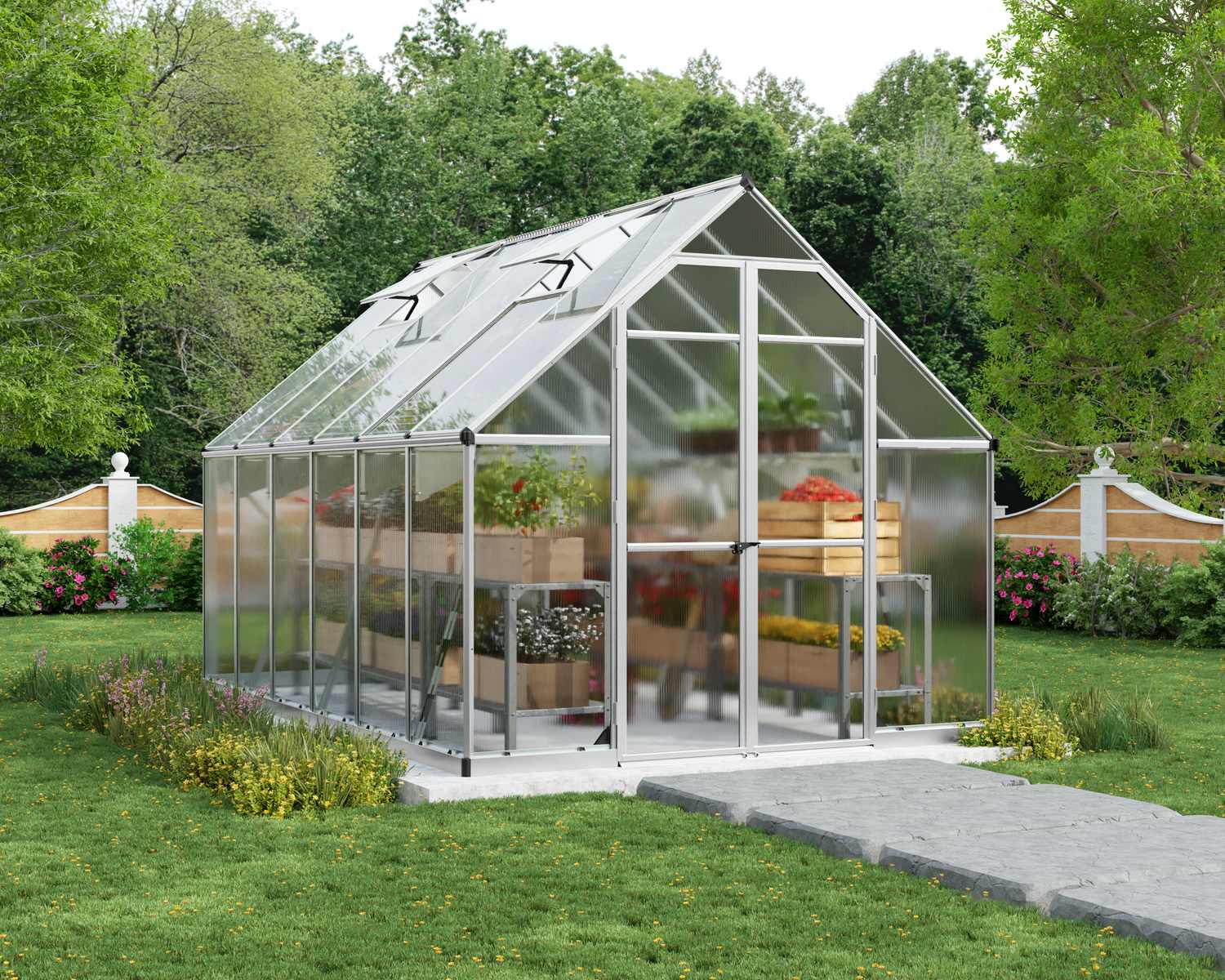 8ft x 12ft silver Essence greenhouse with a sturdy aluminum frame and clear polycarbonate panels, set in a garden with lush greenery and a path