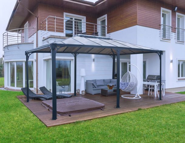 Aluminum grey gazebo Martinique 12'x16' with polycarbonate roof panels lean to house on a deck patio with garden furniture