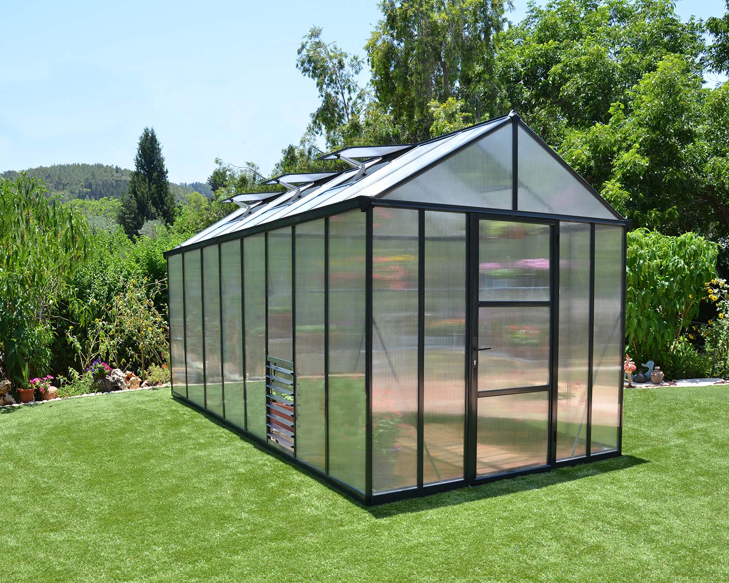 8ft x 16ft grey Glory greenhouse with a durable aluminum frame and multi-wall polycarbonate panels, set in a vibrant garden