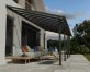 Grey Olympia patio cover, 3m x 8.6m, with an aluminum frame and clear polycarbonate panels, offering shade and protection for outdoor spaces