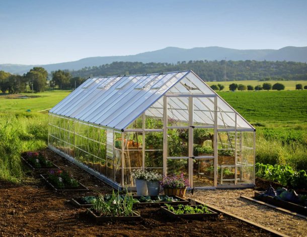 10ft x 28ft silver Balance greenhouse with an aluminum frame and clear polycarbonate panels, set in a garden