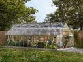 10ft x 24ft silver Balance greenhouse with an aluminum frame, clear polycarbonate panels, filled with plants, in a backyard with a wooden fence