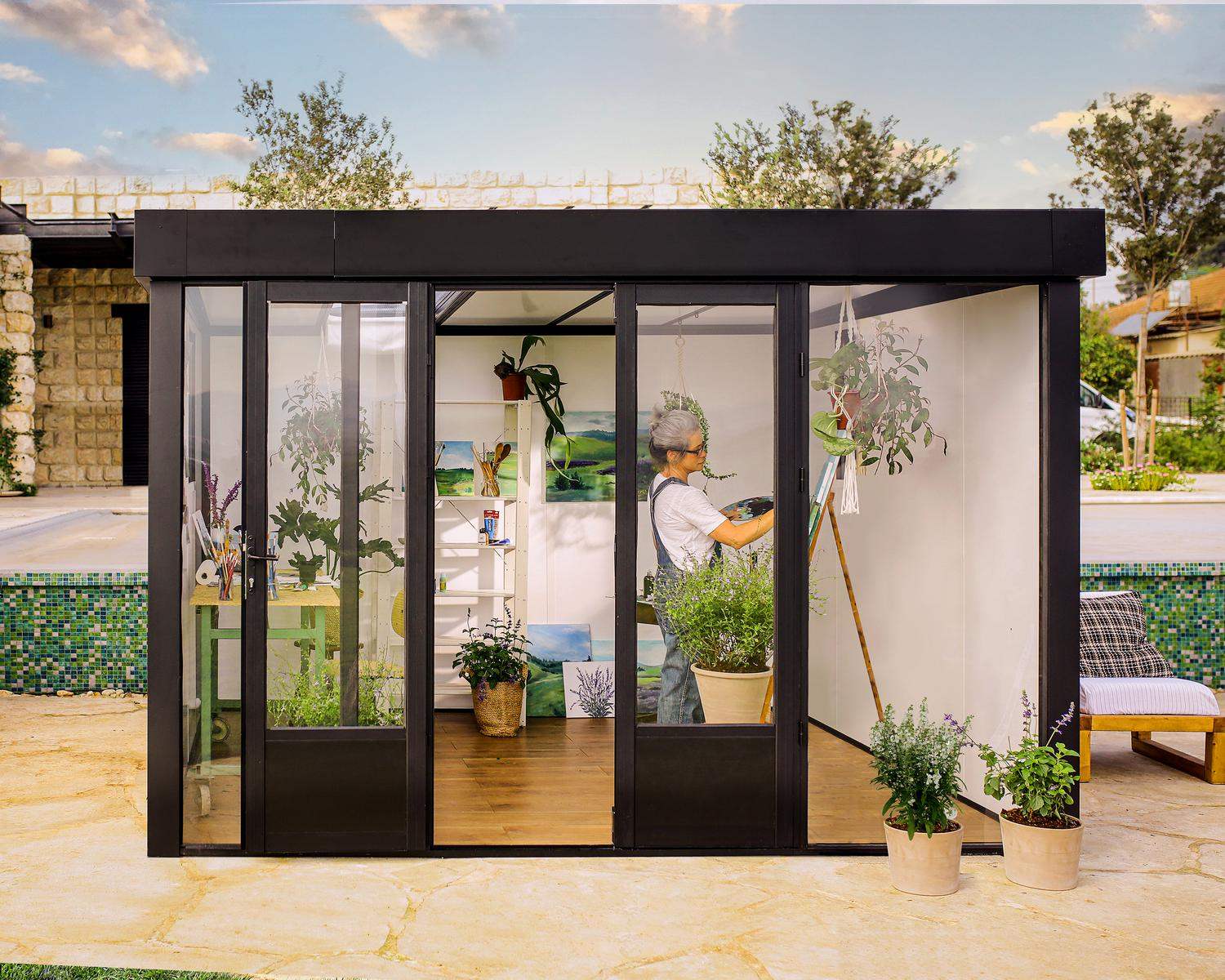 Stylish Copenhagen 3m x 3.5m black Lean to Conservatory with an aluminum frame and clear polycarbonate panels, set in a serene garden at sunset