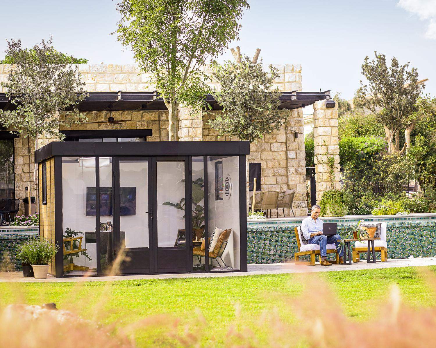 Stylish Copenhagen 3m x 3.5m black Lean to Conservatory with an aluminum frame and clear polycarbonate panels, set in a serene garden at sunset