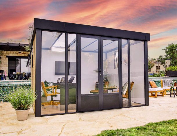 Stylish Copenhagen 3m x 3.5m black enclosed gazebo with an aluminum frame and clear polycarbonate panels, set in a serene garden at sunset