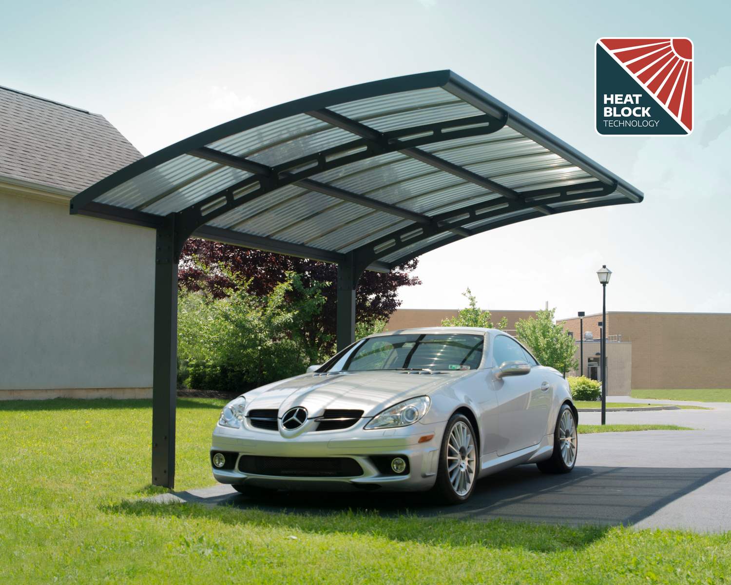 10ft x 16ft Arizona Wave carport with a grey aluminum frame and polycarbonate roof, sheltering a sports car next to greenery