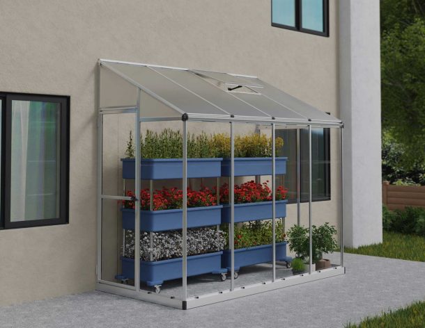 8ft x 4ft silver Lean-To Grow House with clear polycarbonate panels, aluminum frame, and plants inside during a snowfall