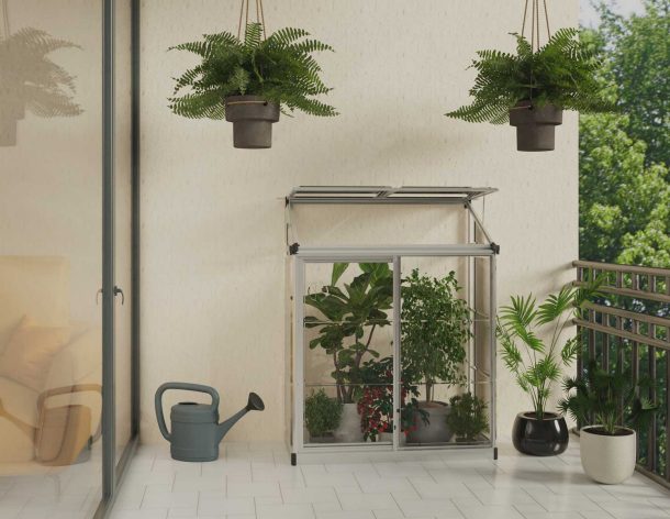 4ft x 2ft silver Lean-To Grow greenhouse with clear polycarbonate panels and an aluminum frame, attached to a wall, surrounded by snow