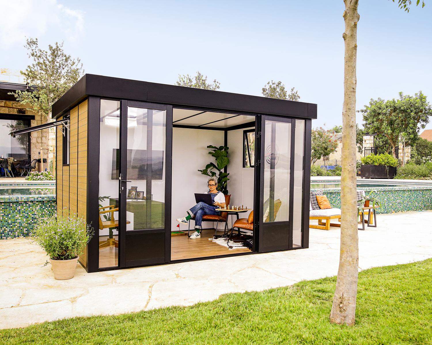 Copenhagen 3m x 3.5m black lean-to conservatory with an aluminum frame and clear polycarbonate panels, set in a sunset garden