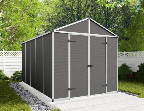 8ft x 12ft grey Rubicon garden shed with a strong aluminum frame and polycarbonate panels, nestled among greenery and a white fence
